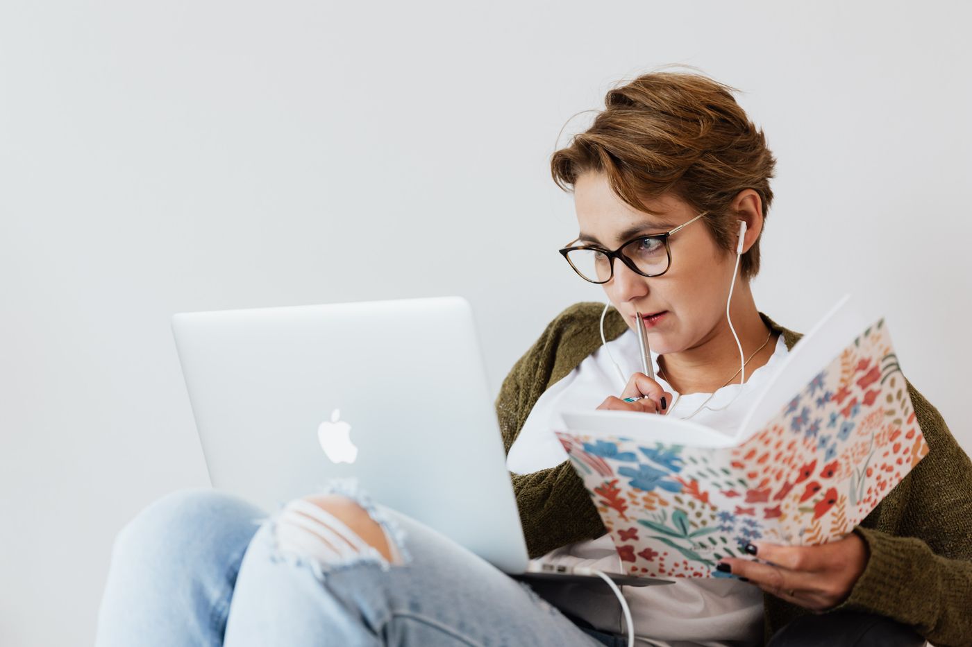 Una donna adulta studia al computer portatile prendendo appunti su un quaderno