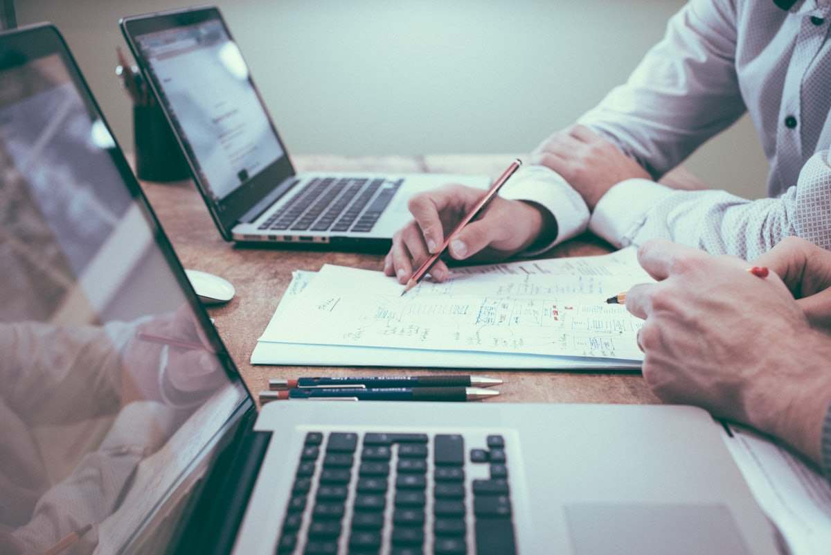 Due professionisti analizzano documenti e dati davanti a due computer portatili