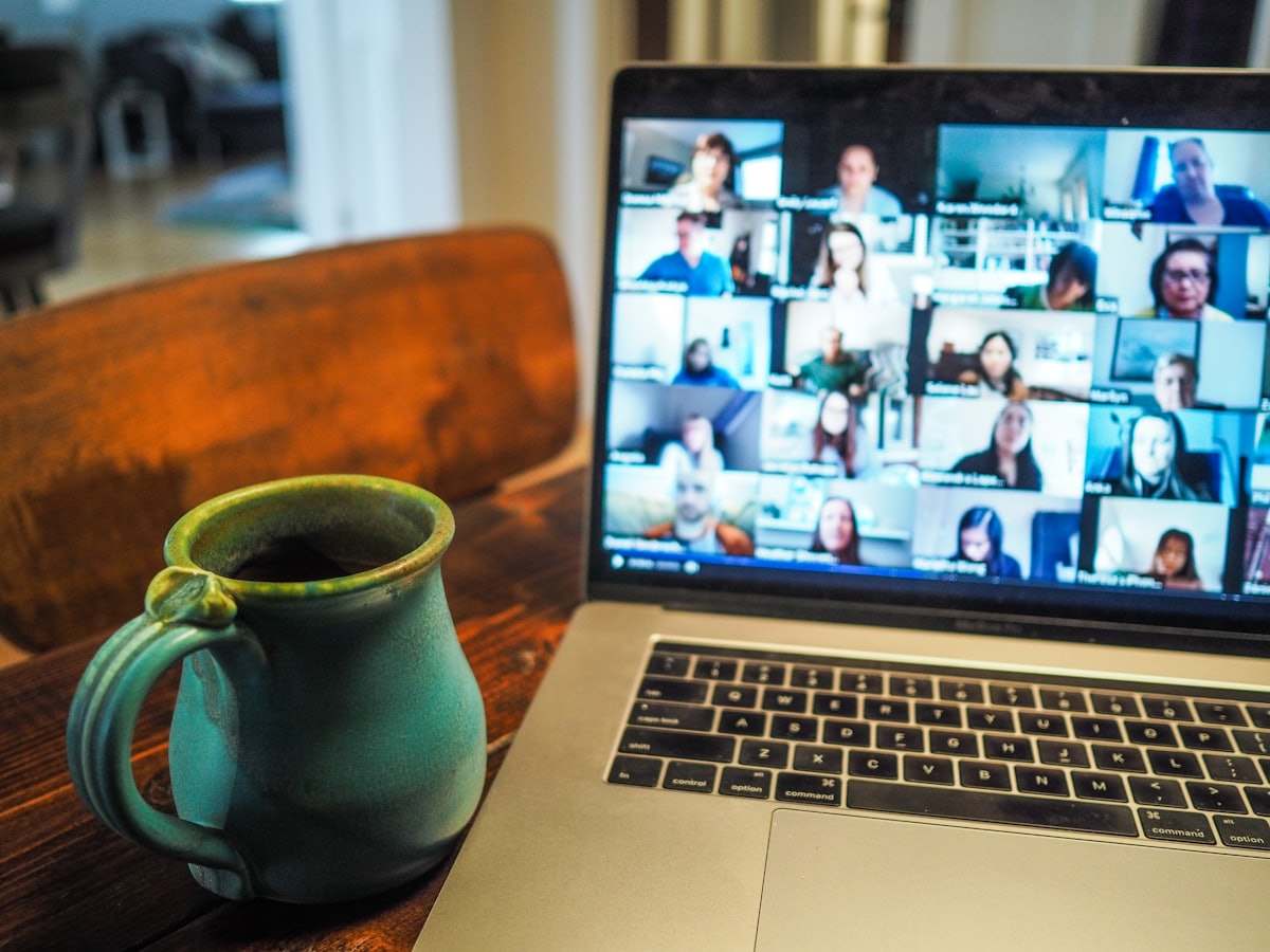 Computer portatile con una videoconferenza a griglia, accanto a una tazza